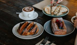 a hand slicing decadent pastries on the table at Wildflour Bakery in Canberra